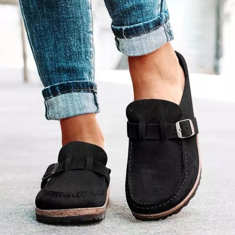 Black suede loafers with buckle detail, worn with rolled-up blue jeans, showcasing casual footwear style. Perfect for fashion-forward, comfortable walking.