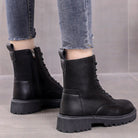 Black leather combat boots with chunky soles and side zippers, worn with frayed hem jeans. Stylish women's footwear for casual fashion.