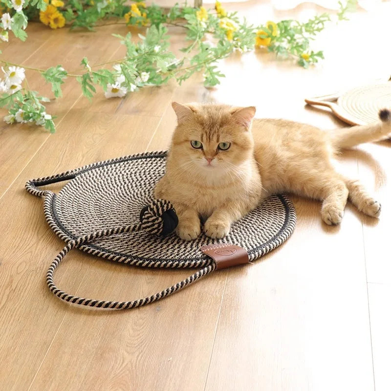 Fluffy orange cat sitting on a woven rope mat on wooden floor, surrounded by green plants and yellow flowers. Cozy pet decor, indoor cat relaxation.