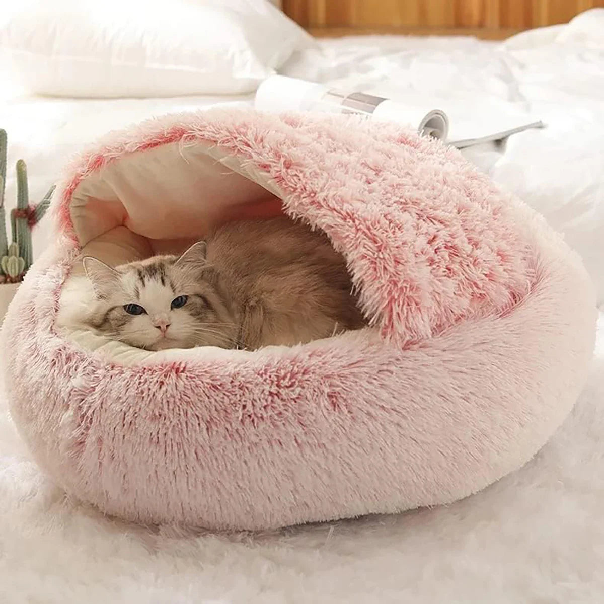Fluffy pink cat bed with a cozy design, featuring a relaxed cat inside, perfect for pet comfort.