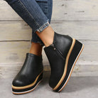 Black platform ankle boots with side zipper, worn with frayed hem jeans. Stylish women's footwear, casual fashion, elevated sole, modern design.