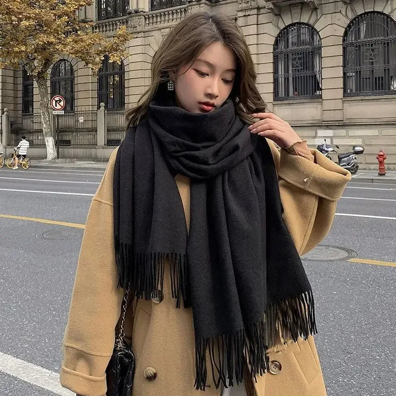 Woman in oversized camel coat and black scarf walking on city street; stylish fall fashion, urban background, trendy outerwear, autumn style.