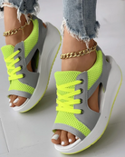 Neon green mesh open-toe sneakers with chunky white platform soles and gray accents, paired with frayed jeans and gold ankle chain. Fashion footwear.