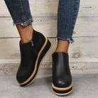 Black platform ankle boots with side zippers, worn with frayed hem skinny jeans. Stylish women's footwear, casual fashion, trendy shoe design.