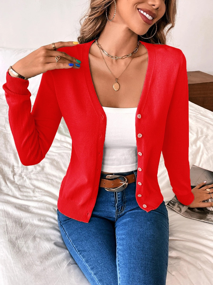 Woman wearing red cardigan, white tank top, blue jeans; casual fashion outfit.