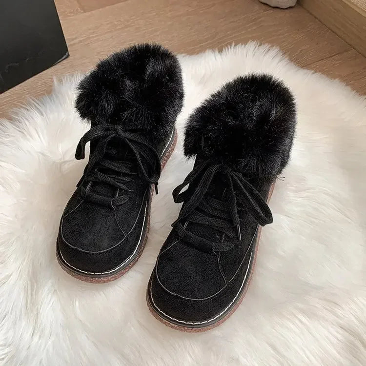 Black suede winter boots with faux fur lining on a white fluffy rug, featuring lace-up design and stitched detailing, perfect for cold weather fashion.