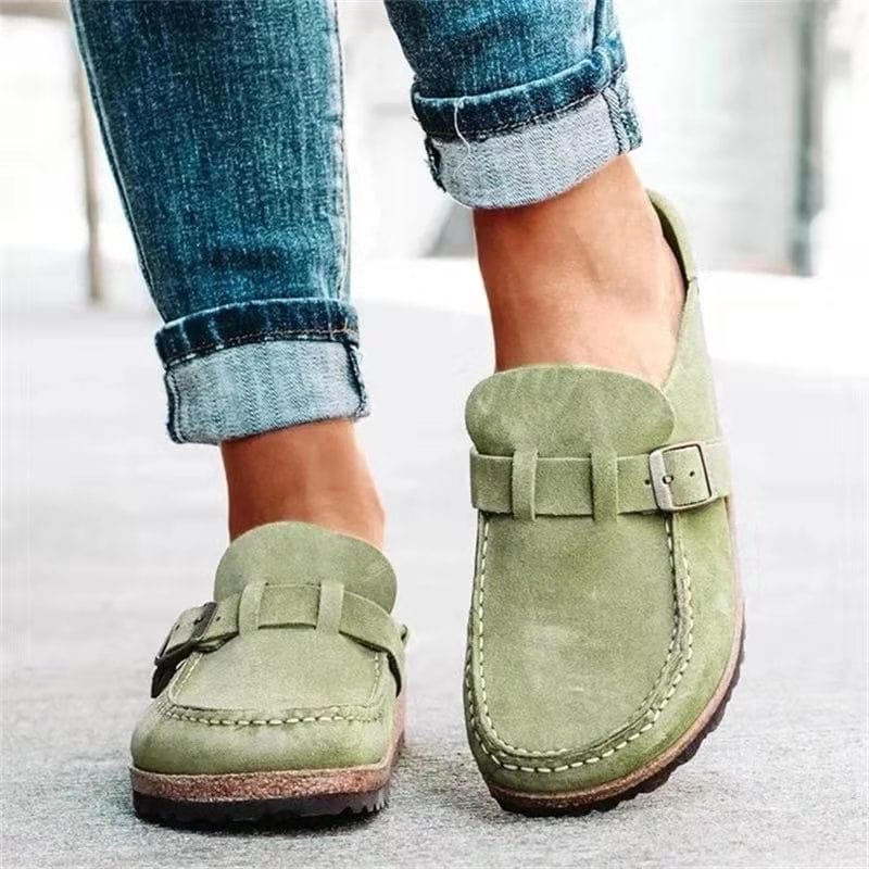 Green suede loafers with buckle detail worn with rolled-up blue jeans, showcasing casual footwear style. Perfect for fashion-forward, comfortable walking.