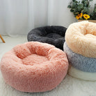 Fluffy round pet beds in pink, gray, cream, and blue colors on a soft white carpet, ideal for cats and small dogs, enhancing cozy home decor.