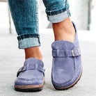 Blue suede loafers with buckle detail worn by a person in rolled-up jeans, showcasing casual footwear style. Perfect for fashion-forward comfort.