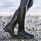 Black leather riding boots on rocky beach terrain, showcasing durable equestrian footwear. Perfect for outdoor activities and stylish fashion.