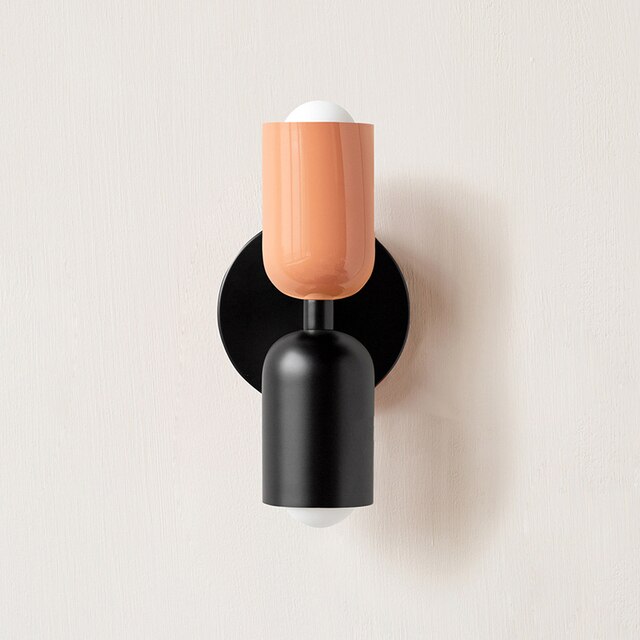 Modern wall sconce with black and orange cylindrical design, minimalist lighting fixture, contemporary home decor, energy-efficient LED bulb.