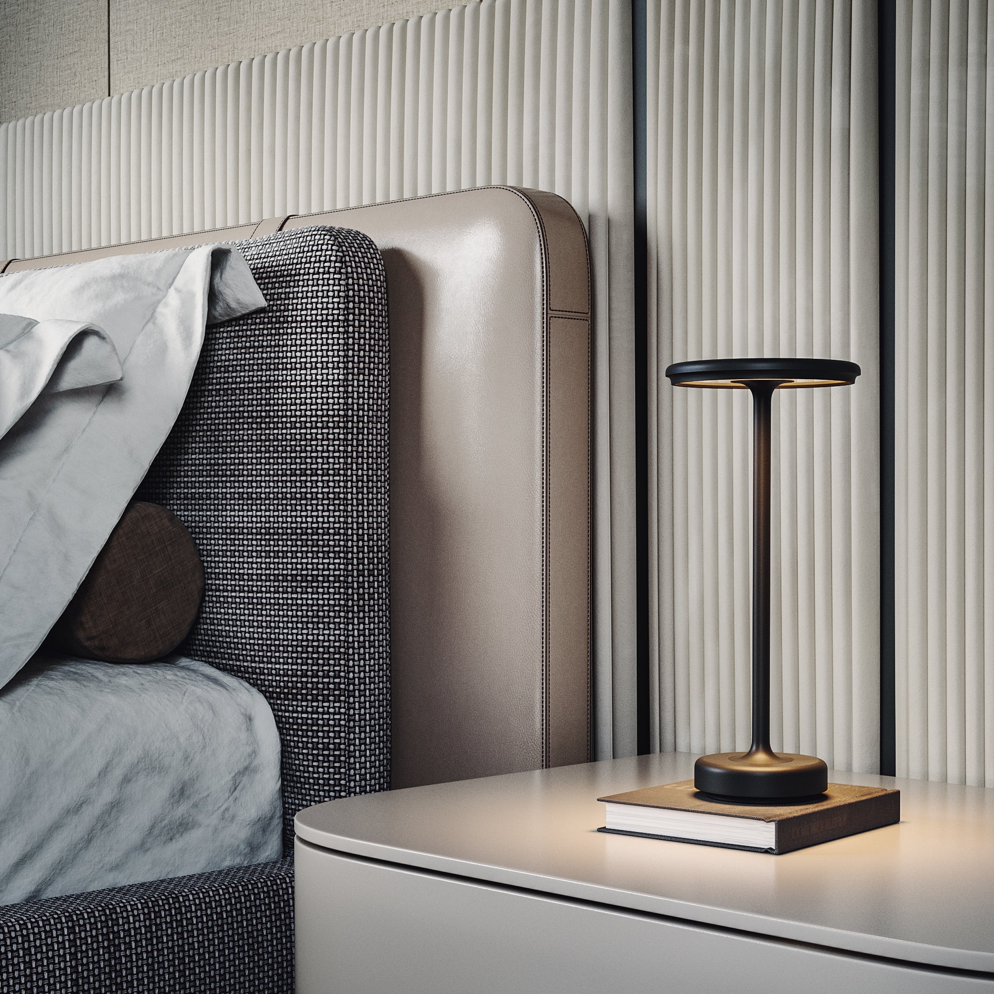 Modern black table lamp on a bedside table, next to a bed with textured headboard. Sleek design, ideal for contemporary bedroom decor.