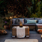 Outdoor patio with wicker furniture set, featuring a cozy sofa and a coffee table with a tabletop fire pit. Ideal for garden relaxation and evening ambiance.