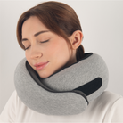 Woman using a gray travel neck pillow with adjustable strap, providing comfort and support. Ideal for travel, ergonomic design, soft fabric.