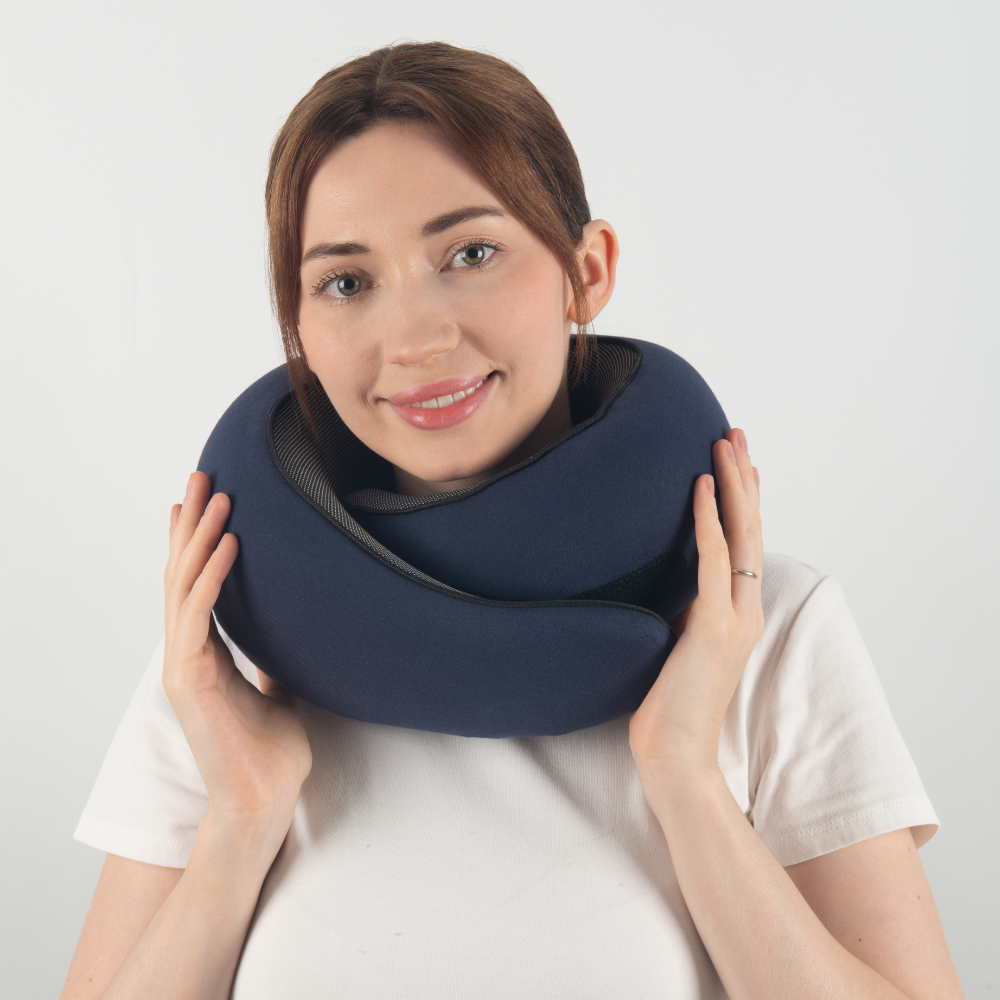 Woman wearing a blue travel neck pillow, ergonomic design, comfortable support, ideal for flights and long journeys, travel accessory.