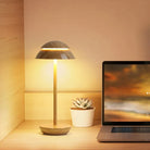 Modern wooden table lamp with warm LED light, next to a laptop and succulent plant on a desk. Stylish home office decor, minimalist lighting.