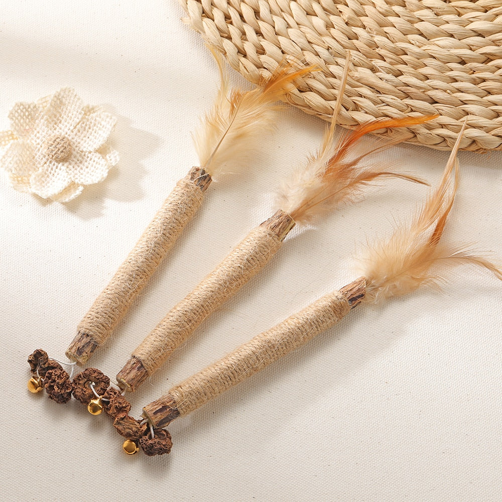 Three natural sisal cat toys with feathers and bells on a woven mat, perfect for interactive play and scratching. Eco-friendly pet accessories.