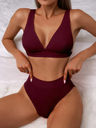 Woman modeling burgundy bikini set with high-waisted bottoms and V-neck top, showcasing swimwear fashion, beachwear style, and summer trends.