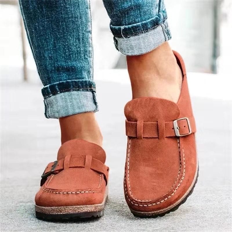 Women's casual brown suede loafers with buckle detail, worn with rolled-up jeans. Comfortable slip-on shoes for everyday fashion and style.