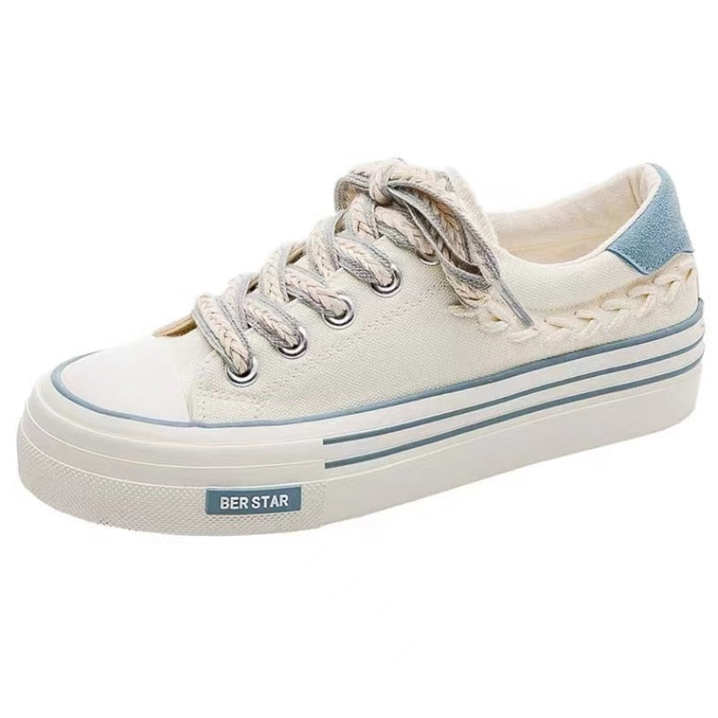 White canvas sneaker with braided lace detail, blue heel accent, and platform sole. Casual footwear, trendy design, perfect for everyday wear.