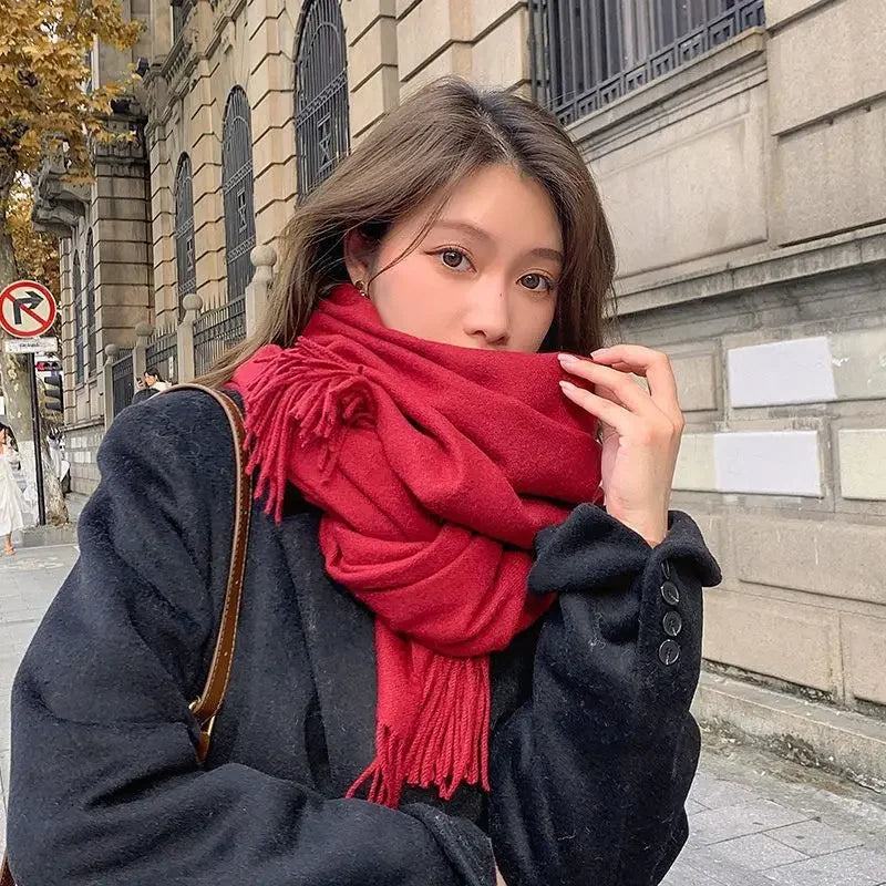 Woman in stylish black coat and red scarf on city street, autumn fashion, urban background, cozy winter outfit, trendy seasonal clothing.