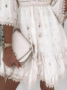 White lace dress with intricate embroidery, paired with a beige crossbody bag and gold watch. Elegant summer fashion, boho chic style.