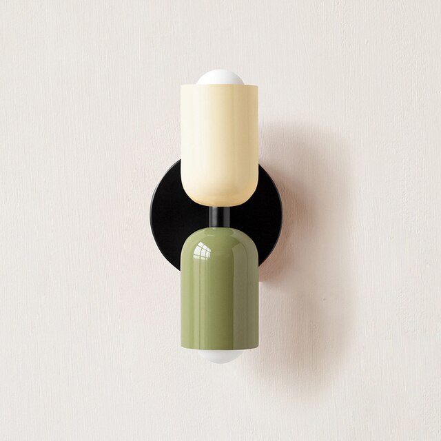 Modern wall sconce with dual-tone design, featuring a beige and green cylindrical shade on a black base. Contemporary lighting fixture for home decor.