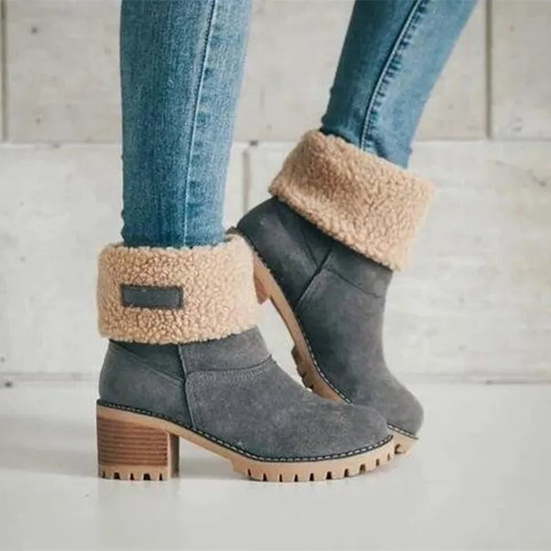 Gray suede ankle boots with faux fur lining, block heels, and rugged soles, paired with blue jeans. Stylish winter footwear for women.