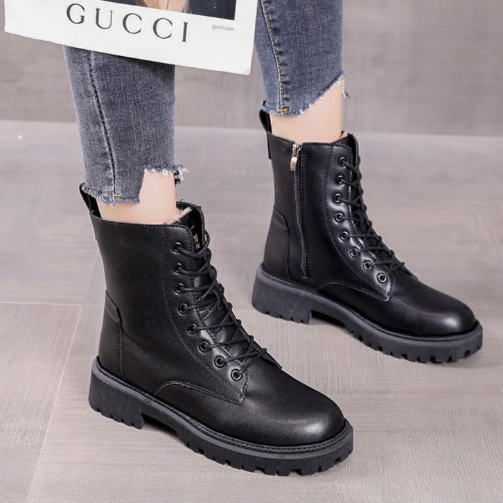 Black leather combat boots with chunky soles and lace-up design, paired with distressed jeans. Fashionable footwear for women.