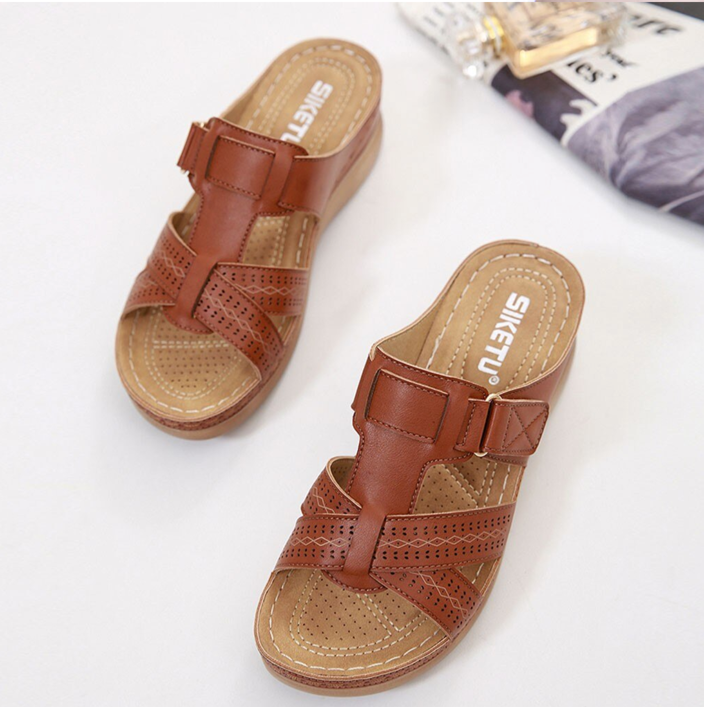 Brown leather women's sandals with perforated design and wedge heel, featuring adjustable straps. Perfect for casual summer wear.