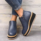 Women's blue leather wedge ankle boots with side zippers, paired with frayed hem jeans. Stylish, comfortable footwear for casual fashion.