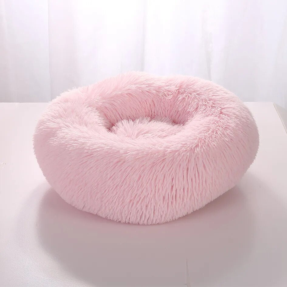 Fluffy pink pet bed, round donut shape, soft faux fur, cozy and comfortable for cats and small dogs, perfect for pet relaxation and sleep.