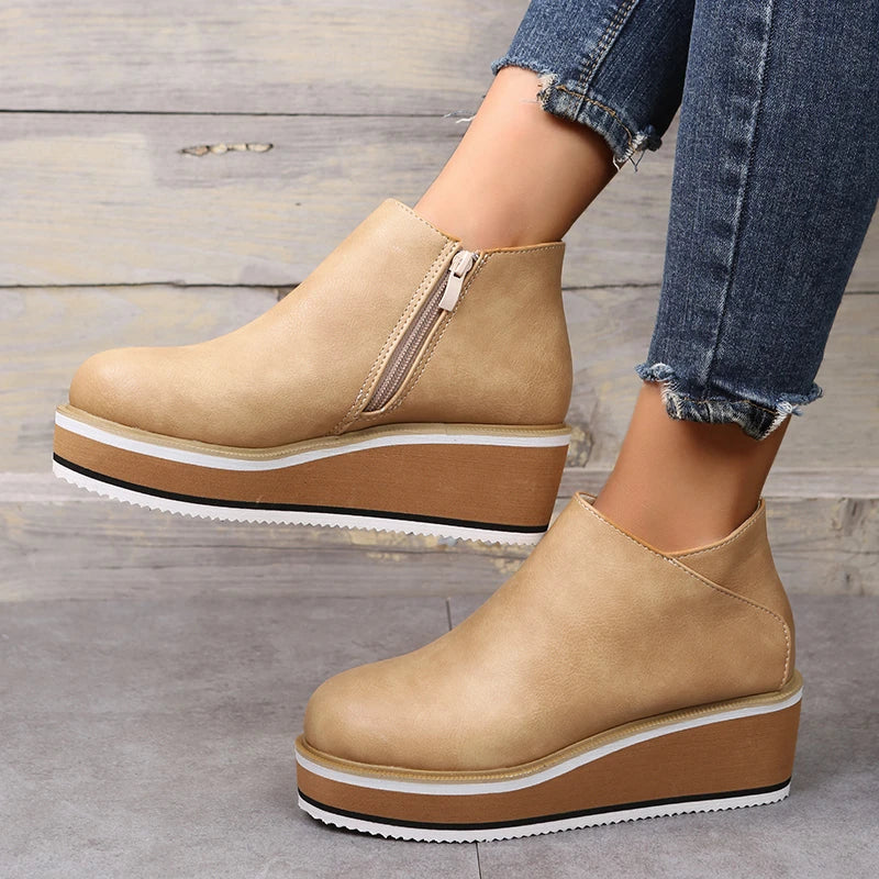 Beige platform ankle boots with side zipper, paired with distressed denim jeans. Fashionable women's footwear, casual style, comfortable design.