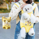 Woman carrying fluffy white dog in a yellow pet carrier backpack with teddy bear design, outdoors. Cute pet accessory, dog travel gear.