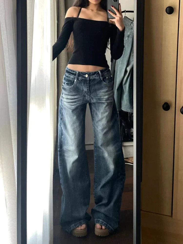 Woman wearing off-shoulder black top and wide-leg jeans, taking a mirror selfie. Fashionable casual outfit, trendy denim style, modern wardrobe.