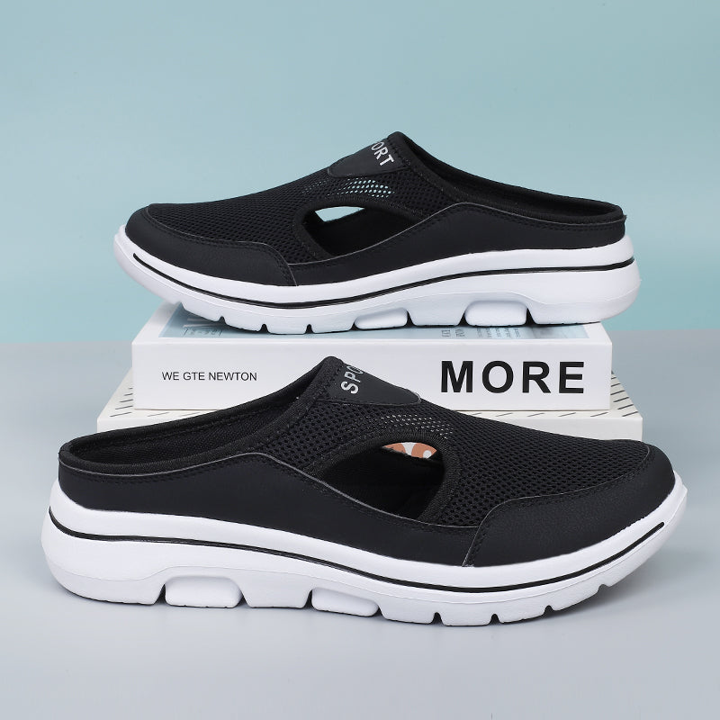 Black slip-on athletic shoes with breathable mesh upper and white cushioned sole, displayed on a box against a light blue background.