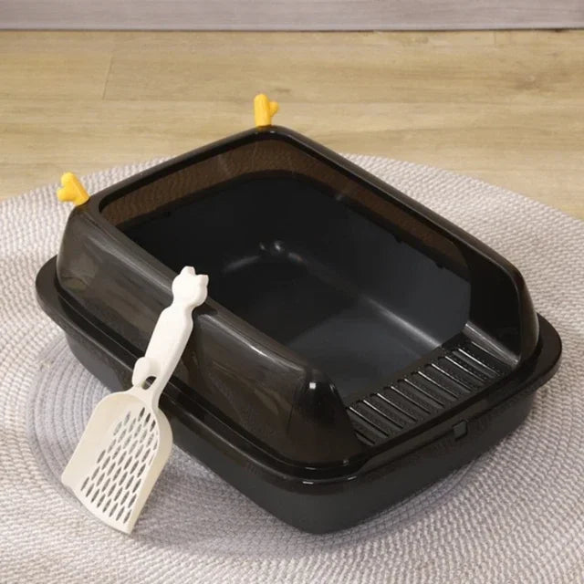 Black plastic cat litter box with high sides and white scoop on a gray rug.
