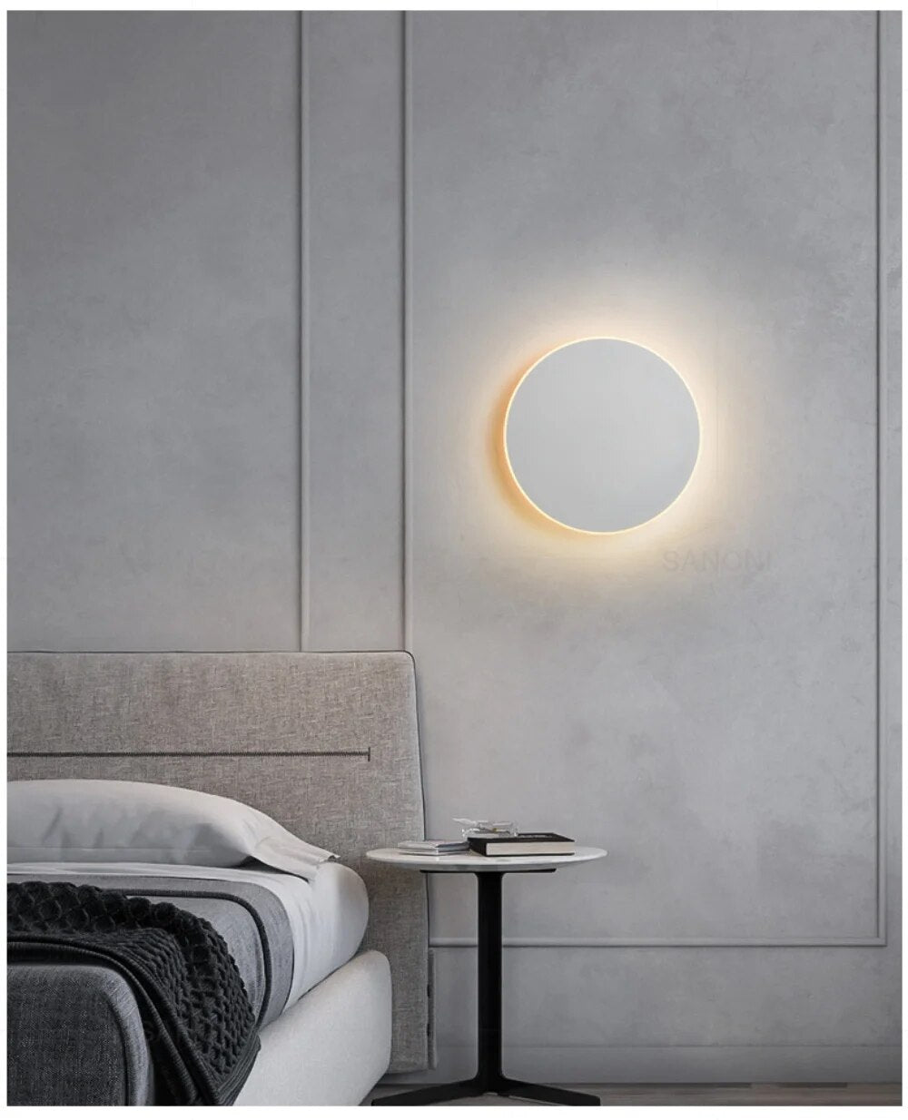 Modern bedroom with minimalist round wall light, gray upholstered bed, and sleek black side table. Contemporary interior design, cozy ambiance.