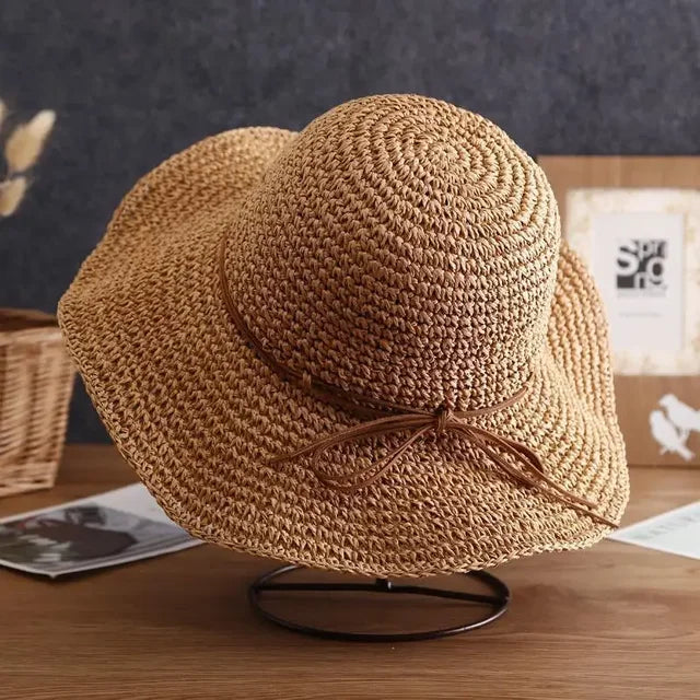 Straw sun hat for women with wide brim and decorative bow, perfect for summer beach outings and sun protection. Stylish and lightweight accessory.