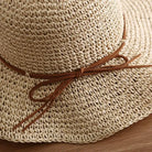 Straw sun hat for women with brown leather bow, perfect for summer beach outings. Lightweight, breathable, and stylish sun protection accessory.