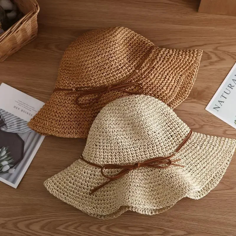 Two stylish women's straw sun hats with brown ribbons on a wooden table, perfect for summer beachwear and sun protection.