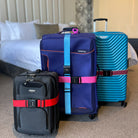 Three suitcases with colorful luggage straps in a hotel room; black, blue, and teal suitcases secured with red, blue, and pink straps.