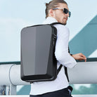 Sleek black anti-theft backpack with hard shell design, worn by a man in sunglasses. Ideal for tech gear, travel, and urban commuting.