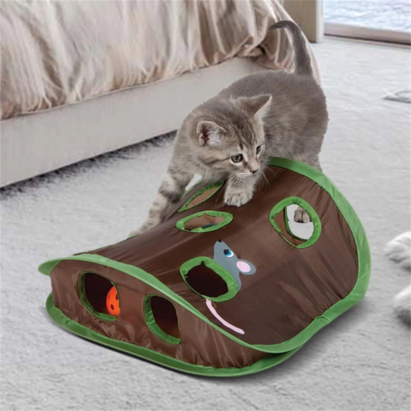 Kitten playing with interactive cat toy tunnel, featuring multiple holes and colorful design, perfect for indoor pet entertainment and exercise.