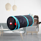 Cat play tunnel with hanging toys in a modern living room, featuring a plush cat doll wearing a hat and glasses. Perfect for pet entertainment and decor.