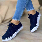 Women's casual black sneakers with white soles, lace-up design, paired with frayed hem jeans. Stylish footwear for spring fashion trends 2023.