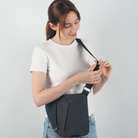 Woman wearing a stylish black crossbody sling bag, adjusting strap. Casual fashion, white t-shirt, denim jeans. Ideal for travel, everyday use.