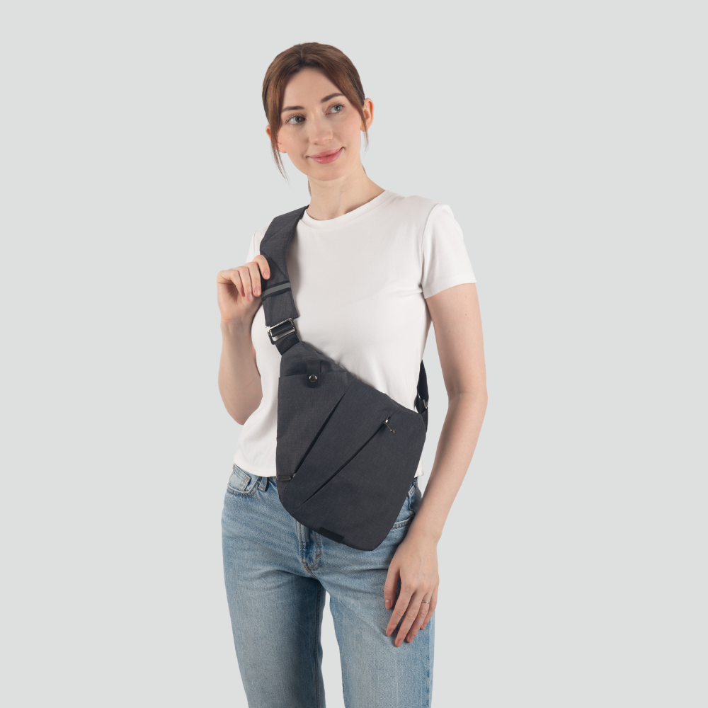 Woman wearing a stylish black crossbody sling bag over a white t-shirt and jeans, showcasing modern fashion accessories for casual outings.