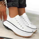 White platform sneakers with chunky soles and black accents, worn with black pants. Fashionable footwear for casual style and comfort.