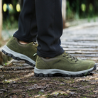 Green hiking shoes on a person walking outdoors, featuring durable soles and breathable material, ideal for trekking and outdoor adventures.